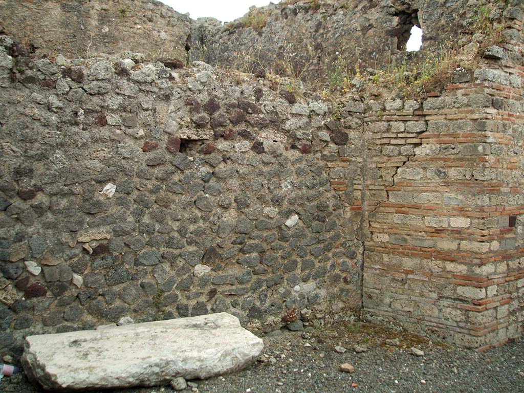 IX.1.32 Pompeii. May 2005.
Site of steps to upper floor against east wall of atrium. The base of the steps can just be seen in the south-east corner, centre-right.
According to Warscher, “the large white block of tufa seen in the above photo was probably one side of the impluvium of the atrium of IX.1.32”.