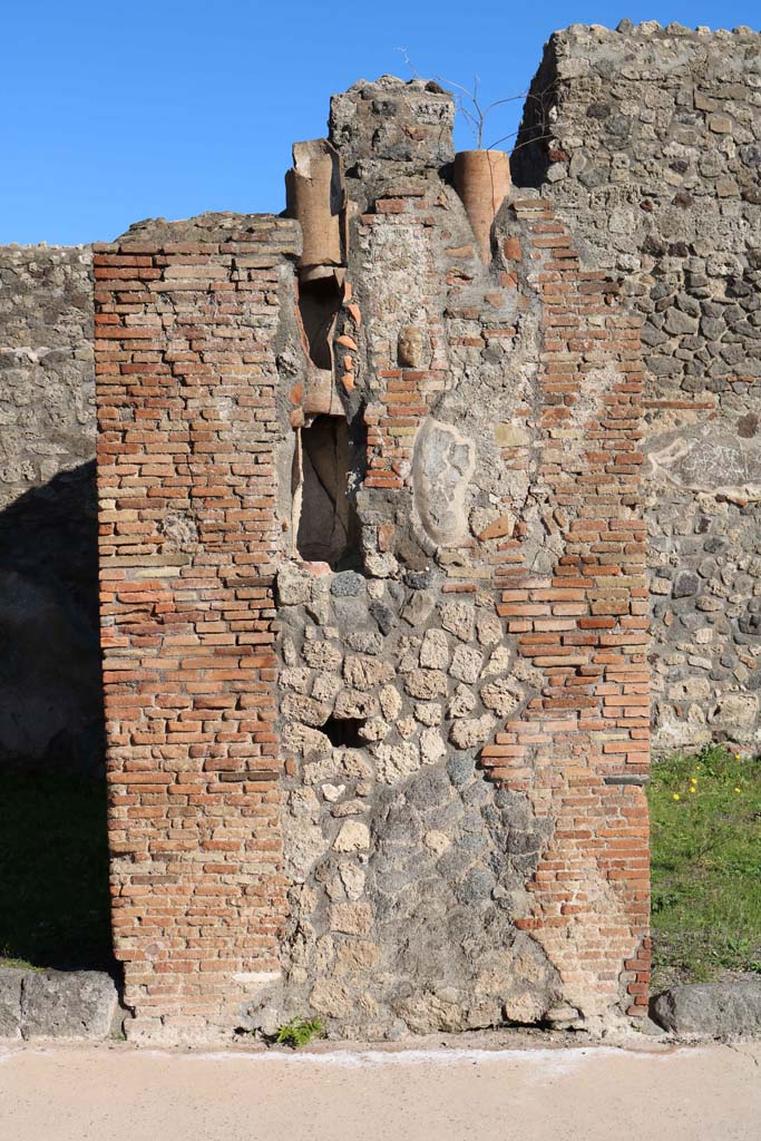 IX.2.2, on left, and IX.2.3, on right. December 2018.
Central pilaster with downpipe. In the centre of the pilaster is a small terracotta face.
Photo courtesy of Aude Durand.