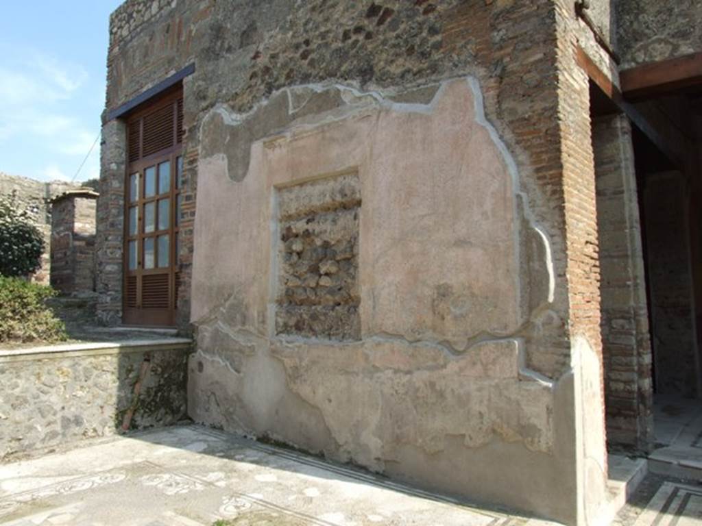 IX.3.5 Pompeii. March 2009. Room 12, south wall of tablinum. According to Dyer:
“The tablinum was raised by one step above the floor of the atrium. Its floor consists of a white marble mosaic, surrounded with narrow black borders. In the middle is a slab of giallo antico, encircled with a border of variegated mosaic. The walls are richly decorated with pieces of architecture, and in the middle of them are spaces for two large pictures, which must have been removed before the eruption. The wooden frames in which the pictures were contained have left their impressions on the stucco, as well as the marks of two horizontal supports at the back of them. These marks, which are about two inches deep, have led some writers to suppose that the pictures were painted on wood. Whether, however, there were any such at Pompeii is a moot point; and Overbeck contends that the supports at the back might have served either for a thin stucco tablet or to bind together the pieces of a wooden one. The ceiling of the tablinum was also of stucco, with coloured panels and gilt rosettes in the centre of them, as appears from numerous fragments which were discovered.”
See Dyer, T., 1867. The Ruins of Pompeii. London: Bell and Daldy. (p.84)