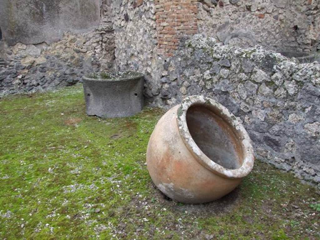 IX.3.20. Bakery. December 2007. Room 1. Remains of terracotta pot and Tufa mill.