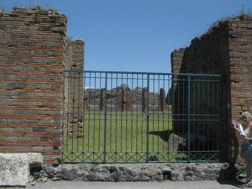 IX.4.5 Pompeii. May 2005. Entrance from Via Stabiana, looking east into the palaestra “d”.
These baths were begun after the 62AD earthquake, and were still under construction at the time of the eruption in 79AD.
The baths occupied this entire insula whose original houses had been demolished to make way for the new baths.
The main entrance “a” was on the Via di Nola at IX.4.18.
An entrance in the unnamed vicolo on the south side at IX.4.10 also led onto the palaestra “d” past a multi seat latrine “e”.
There were two other smaller entrances from Vicolo di Tesmo, probably service doorways, on the eastern side of the insula at IX.4.15 and 16.
IX.4.15 led to service area “t” which contained the furnace area and a small garden divided from it by a wall.
IX.4.16 led to an open area “u” which had a small peristyle and a corridor that led to apodyterium “i”.
During the excavation, the archaeologists found the remains of the demolished residential houses in the area of the palaestra, which had not been entirely cleared by the people building the new baths.
On the east side of the palaestra, on the far side of the green grass in the photo, a depression was found where the large outdoor swimming pool “h” was to built.
Also found was the water channel leading to the latrine “e” (in the room near to IX.4.10), where the waste water from the pool would have been used to flush the latrine.
See Notizie degli Scavi di Antichità, June 1877, (p.445, description and finds).
See BdI 1877, (p.214-223)
See BdI, 1878, (p251- 254)
See La Rocca, De Vos and De Vos, 1976. Guida Archeologica di Pompei. Mondadori Editore, p. 307-9.
