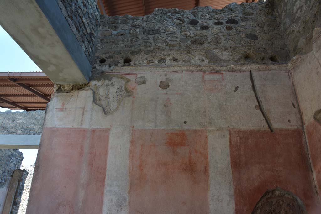 IX.5.11 Pompeii. May 2017. Room e, upper south wall.
Foto Christian Beck, ERC Grant 681269 DÉCOR.
Above a simple black zoccolo with panels separated by compartments, the panels of the middle zone of the wall were delimited by architectural views on a white background, containing medallions with couples: in the white upper area was a masculine figure with palm in his left hand and a crown in the right hand.