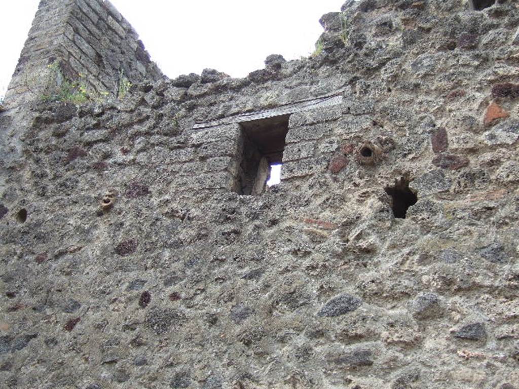 IX.5.13 Pompeii. May 2006. Faces in stonework high up on front wall.