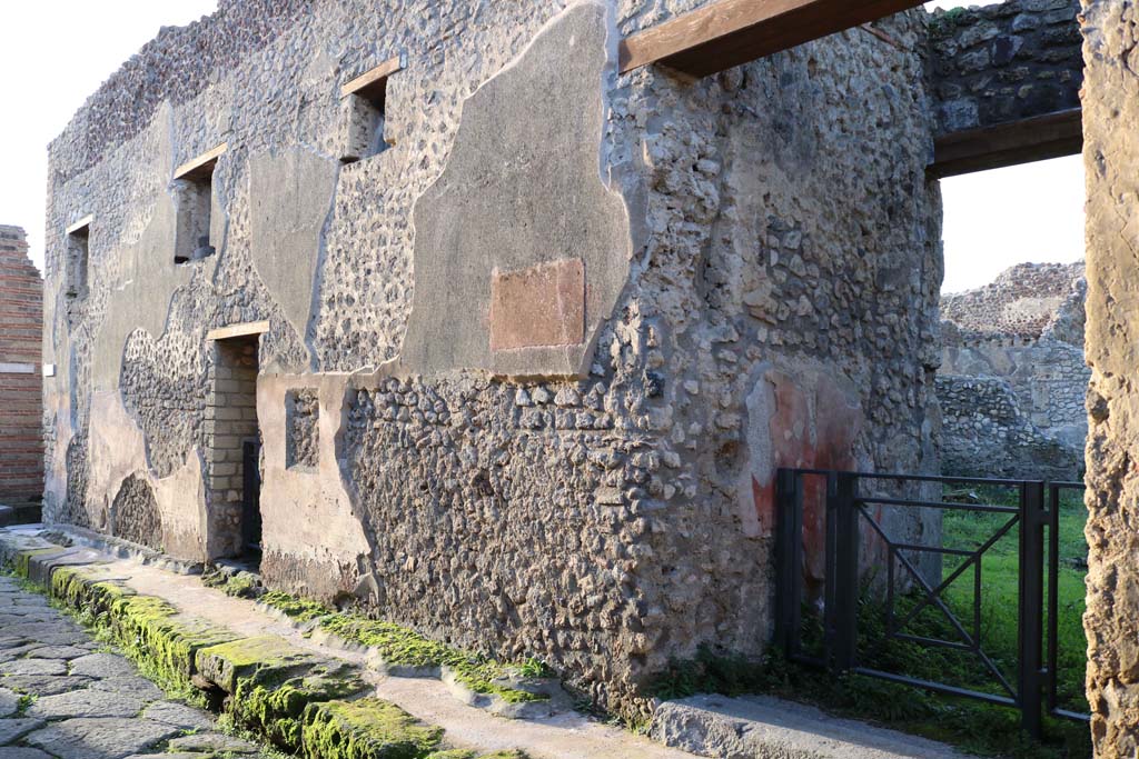 IX.5.19 Pompeii, on left, and IX.5.18, on right. December 2018. Entrance doorways. Photo courtesy of Aude Durand.
According to PPM –
The plaster of the coating was roughly executed, other than on the lower part, which until the height of 1.90m from the ground, was painted with black panels squared with red bands. To the left of entrance no. 18, above the painted zone, was a rectangular slab made from red stucco, with side appendages/handles painted in red as if to appear as a “tabella ansata” on which was painted a sign.
The large gaps in the plaster are partly due to the detachment of graffiti (CIL IV 5112-5126).
See Carratelli, G. P., 1990-2003. Pompei: Pitture e Mosaici. IX (9). Roma: Istituto della enciclopedia italiana, (p. 673).