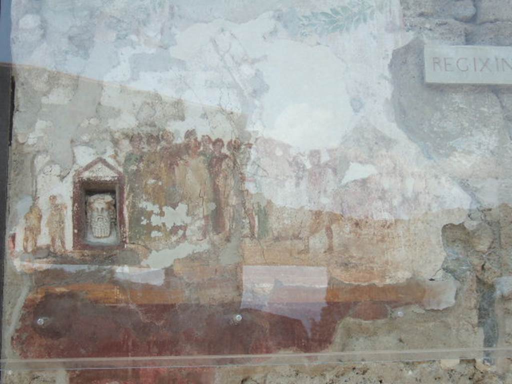 IX.7.1 Pompeii. May 2006. Painting on wall showing procession in honour of the goddess Cybele. Her cult statue is seated on a wooden litter beside which stand four bearers with garlands in their hair. Behind her are two rows of worshippers led by a priest and priestess. Some of the worshippers are playing the Pan pipes or double flute, others beating tambourines or clashing cymbals. See Fröhlich, T., 1991, Lararien und Fassadenbilder in den Vesuvstädten. Mainz: von Zabern. (F63:p.332, T. 59,2).