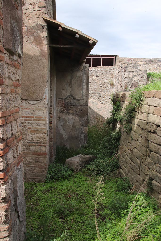IX.7.16 Pompeii. October 2024.
Looking north across atrium 2, towards north-west corner, with doorway to room “a”, under roof, and doorway into room 7.
The entrance corridor 1 is on left. Photo courtesy of Klaus Heese.