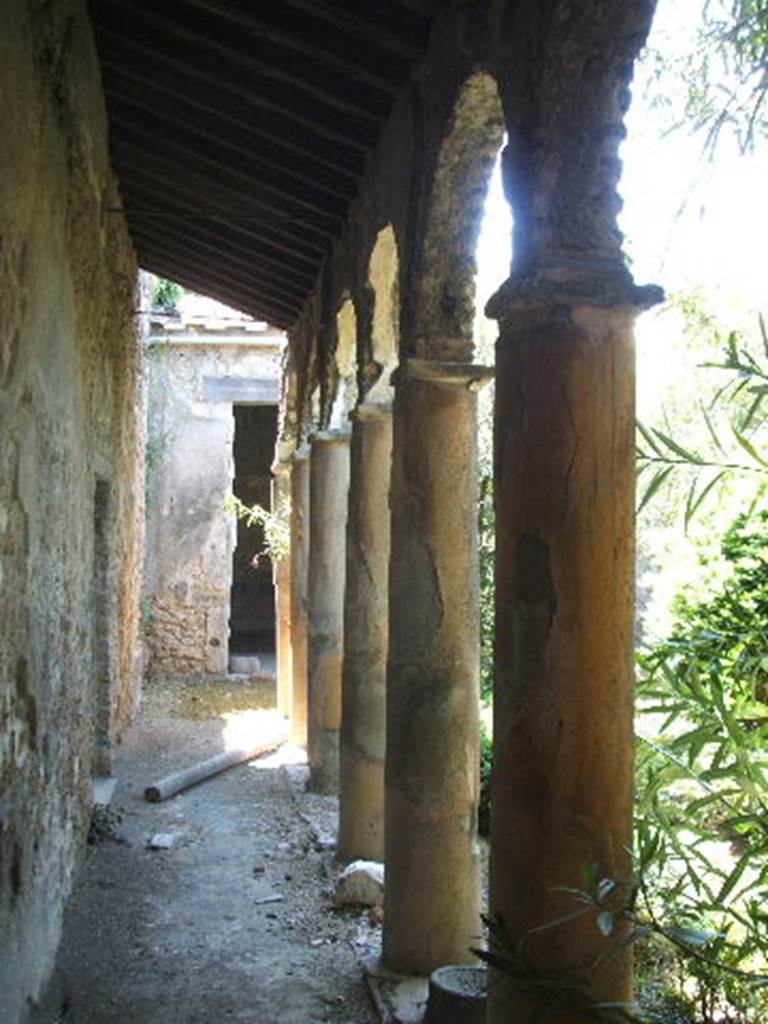 IX.7.20 Pompeii. May 2005. Looking south along east portico.
The doorway that can be seen in the left wall, leads into small room (L), a cubiculum.
Previously this small room, room (L), would have led into a room belonging to IX.7.25.