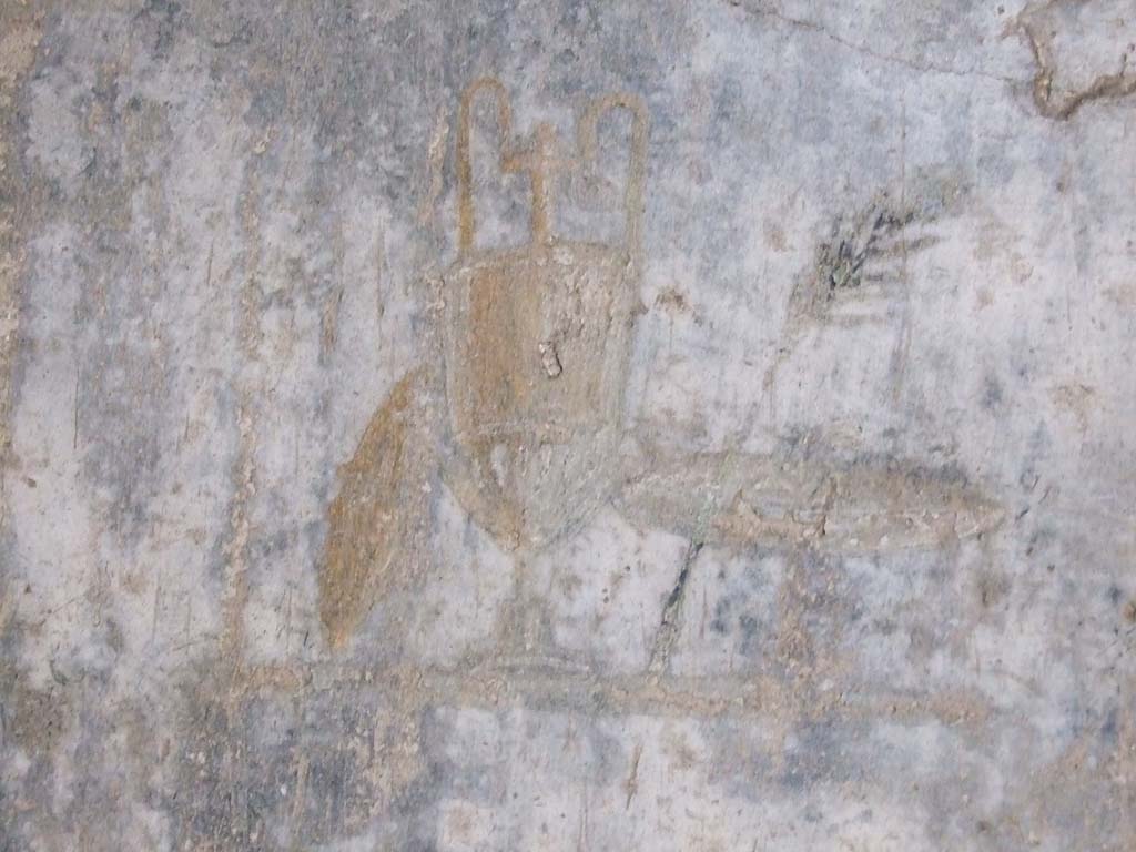 IX.7.20 Pompeii. December 2007.
Room (i), west wall, black panel to south of central painting. Wall painting of trophy vase, small shield and palm.