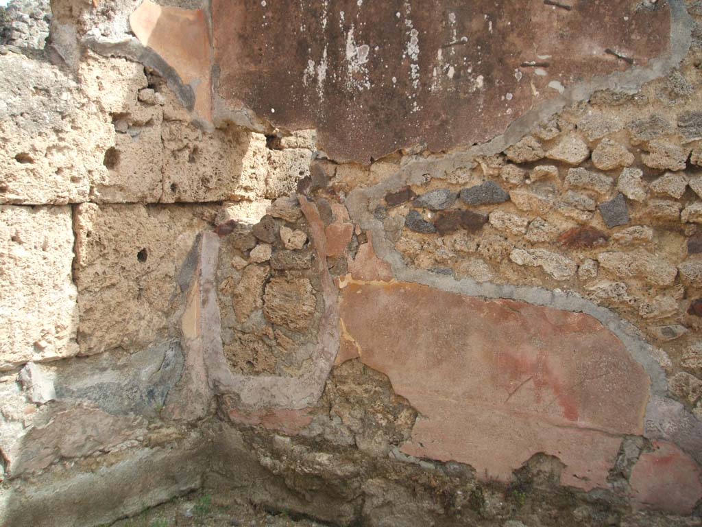IX.7.22 Pompeii. May 2005. Remains of painted plaster in north-east corner of the room on east side of caupona.
According to Mau, this room was the only one that had well conserved plaster.
It was painted simply and clumsily in the last IV style, and on a yellow background.
In the middle of each of the divisions on the walls, there were similar square paintings representing a bird pecking at fruit, on a yellow background.
See Mau in Bullettino dell’Instituto di Corrispondenza Archeologica (DAIR), 1882, (p.194)
According to PPP, the north wall had a red lower area.
The east wall had the lower portion of the walls painted red, in the middle area were narrow red central divisions with yellow panels, the upper area was painted red.
The south wall had the lower portion painted red, the middle section painted yellow with panels.
See Bragantini, de Vos, Badoni, 1986. Pitture e Pavimenti di Pompei, Parte 3. Rome: ICCD. (p.507)