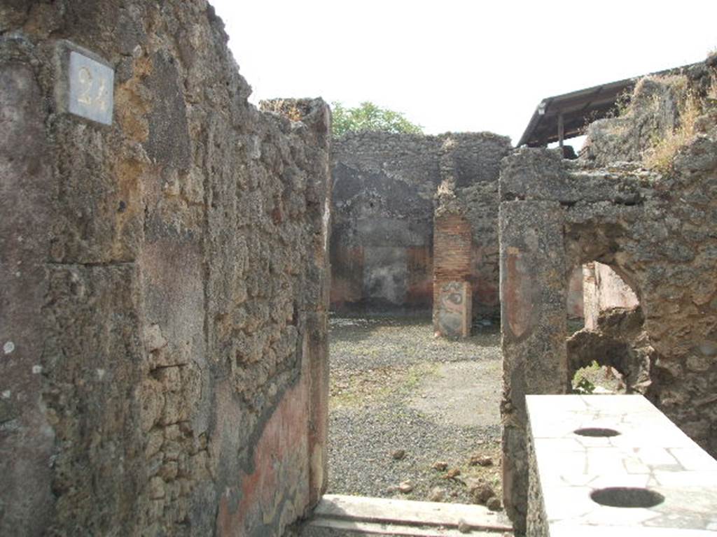 IX.7.24 Pompeii. May 2005. Looking south across thermopolium (a) to doorway to atrium (2) of IX.7.25
The doorway between the shop and the atrium had the threshold of a dark marble and was closed by two battens.
See Mau in Bullettino dell’Instituto di Corrispondenza Archeologica (DAIR), 1882, (p.148)
According to Boyce, in the south wall was a vaulted niche (h.0.44, w.0.44, d.0.51, h. above floor 1.20).
Its inside walls were coated with orange-coloured stucco.
Above the niche was a painting (h.0.30, w.0.73) of the two serpents confronting at an altar.
He references – Not. Scavi, 1880, 395; Bull. Inst., 1882, 148.
See Boyce G. K., 1937. Corpus of the Lararia of Pompeii. Rome: MAAR 14. (p.88 no.443).
