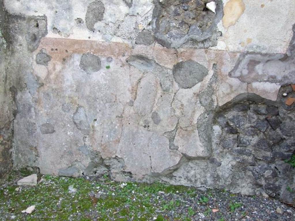 IX.8.2 Pompeii. March 2009. Remains of painted plaster on base of west wall of front room of shop.