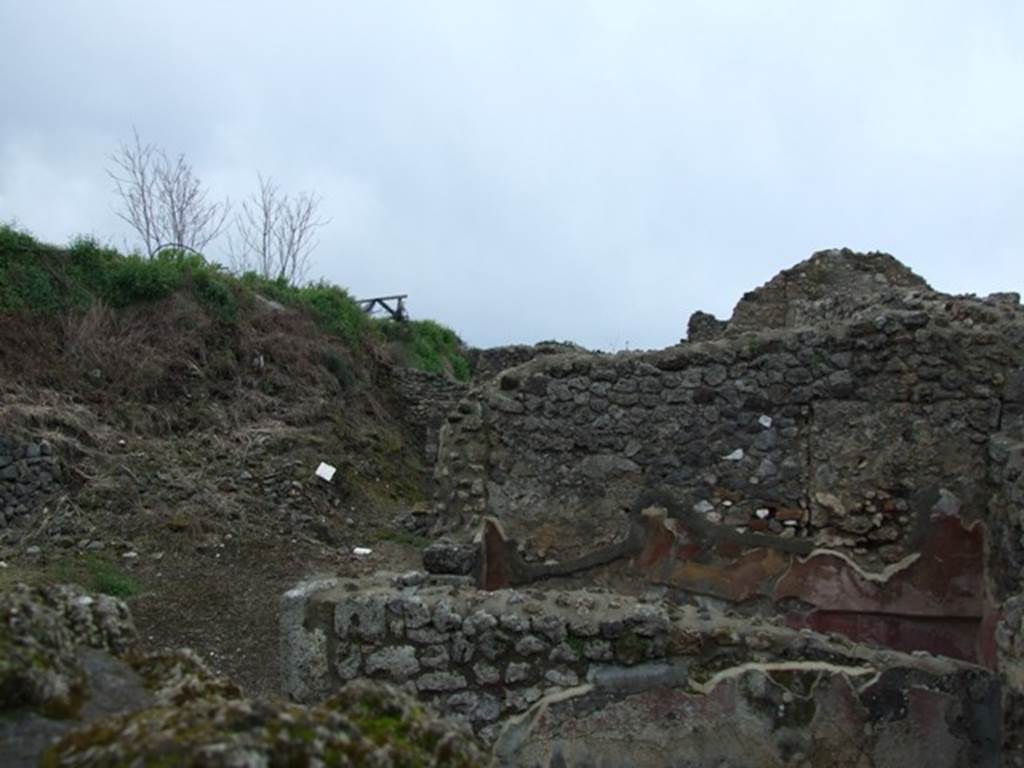 IX.8.c Pompeii. March 2009. Looking south-west from IX.8.6 across exedra to west wall of small room or cupboard. The unexcavated can be seen on the south side of the peristyle.