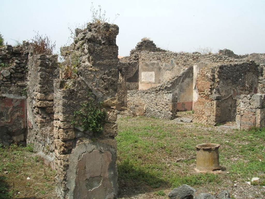 IX.8.c Pompeii. May 2005. Doorway to room on south side of garden area, on left. Looking north west across peristyle with terracotta puteal, towards rooms on north side.