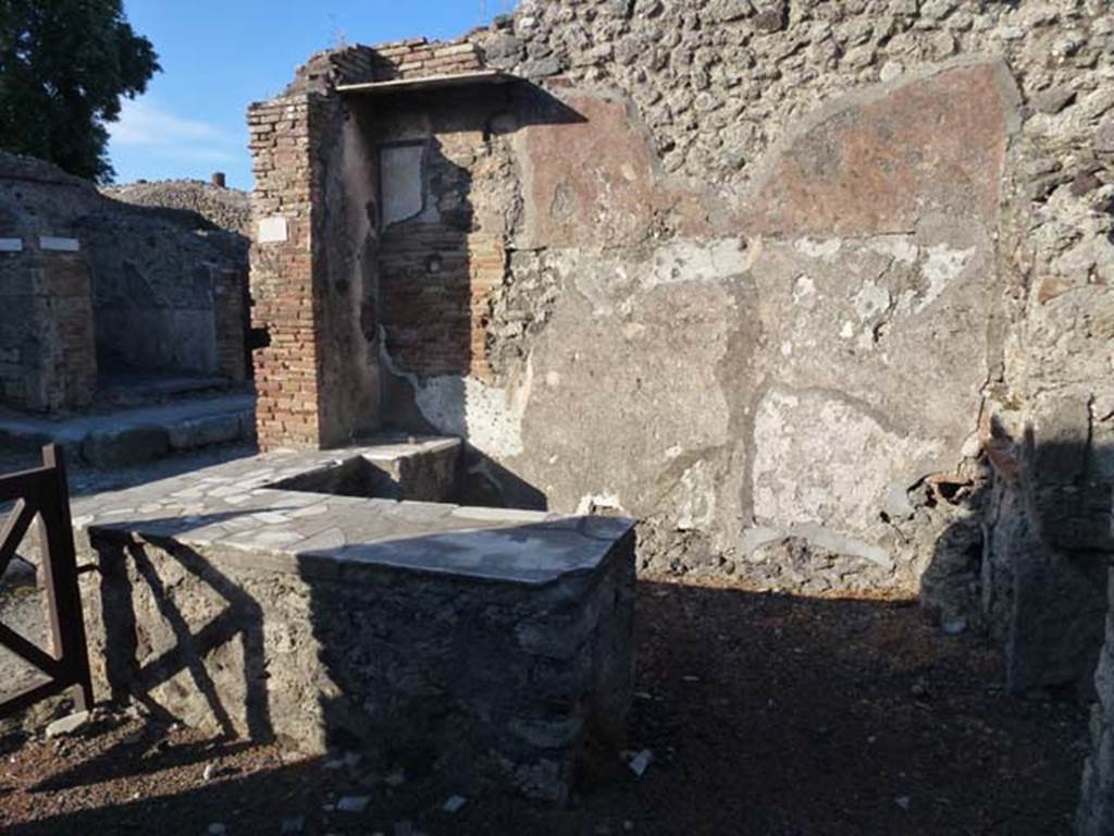 IX.9.8 Pompeii. June 2012. Looking east across bar and counter. Photo courtesy of Michael Binns.
According to NdS, the usual sales-counter was situated near the entrance to the bar.
On the east wall was a painting of a gladiator, (the part that remained being 60 high x 50 wide) which had been covered over and a new layer of plaster applied on top.
When the upper layer fell, the painting reappeared on a white background.
The figure of the gladiator was armed with a crested helmet with perforated visor, a large, curved rectangular shield, and legging on his left leg.
Near his head the following inscription in black letters was read �
AEDIM � SVLL �  XLIX         
        V                               [CIL IV 3789]
See Notizie degli Scavi, 1889, p.126, (note the difference between XLIX above, and Sogliano�s XIIX below).

According to Jacobelli, Sogliano thought that AEDIM was what remained of the gladiator�s name.
His armour indicated that he was a Samnite.
XIIX was the number of contests that he had fought, and the letter V meant he was victorious in that particular contest.
SVLL showed that he belonged to the family �Sullana�.
See Jacobelli, L., 2003. Gladiators at Pompeii. Rome: L�Erma di Bretschneider. 

According to Epigraphik-Datenbank Clauss/Slaby (See www.manfredclauss.de) this read

]aedim(us?) Sull(anus?) XIIX 
V      [CIL IV 3789]
