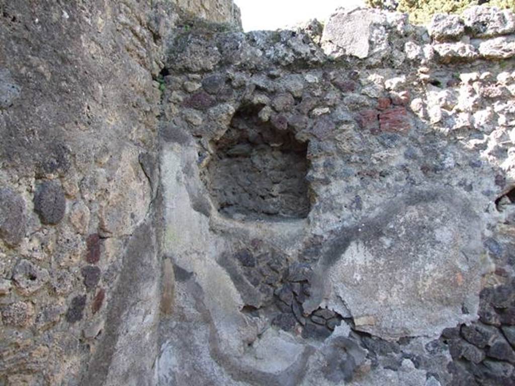 IX.9.12 Pompeii. March 2009. Room 15, remains of niche in north-west corner of kitchen
According to NdS, on the extreme west of the north wall of the kitchen was a rectangular niche, protected by a small roof.
Near this was found the usual painted lararium with Lares, the family Genius sacrificing at the altar, and a tibicine with double flute.
See Notizie degli Scavi di Antichità, 1891, (p.256)
According to Boyce –
In the north wall of the kitchen is a square niche (0.65 square, d.0.25, h. above floor 1.50), with a projecting tile below.
On the wall to the right of it are visible traces of a lararium painting: in the centre, the Genius (h.0.48) with a fold of the toga drawn over his head pours a libation from a patera upon an altar; behind him is the tibicen (h.0.38); on each side stands a Lar (h.0.67) in short tunic, a wreath of leaves upon his head, carrying rhyton and patera.
See Boyce G. K., 1937. Corpus of the Lararia of Pompeii. Rome: MAAR 14. (p.93, no.465).