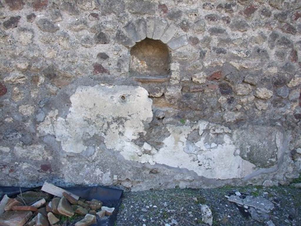 IX.9.a Pompeii. March 2009. Arched niche in west wall, with lararium painting below. According to NdS, the only decoration that remained from the peristyle walls was the lararium painting on the west wall, under the small niche. Here the Genius could be seen sacrificing at an altar, a serpent wrapped around the altar, from the right could be seen a Camillus carrying ribbons and a plate, with a knife for sacrificing the pig. The pig was decorated with a large band around its belly. See Notizie degli Scavi, 1888, p. 515.
