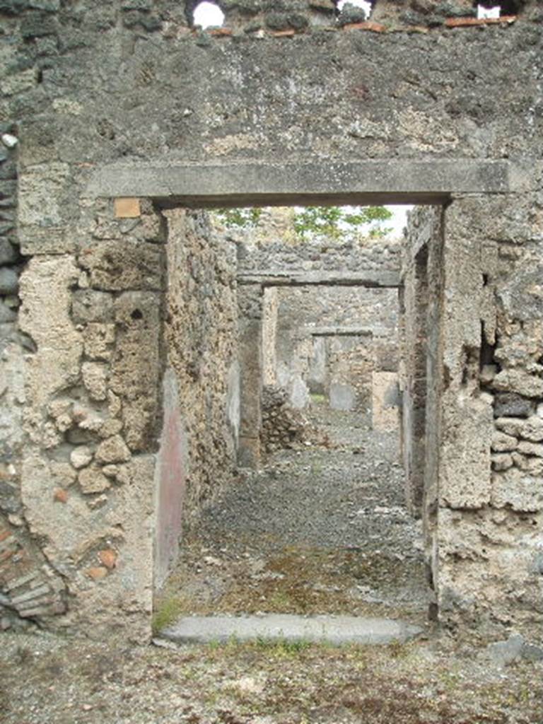IX.9.e Pompeii. May 2005. Entrance doorway, looking east. According to NdS, the entrance doorway had a lava threshold. The doorway led into a long passageway with a beaten floor, the walls were covered with rustic white plaster. The lower section of the walls was covered by a high red zoccolo which was painted with yellow bands to separate it into panels.
See Notizie degli Scavi, 1891, p.255.
