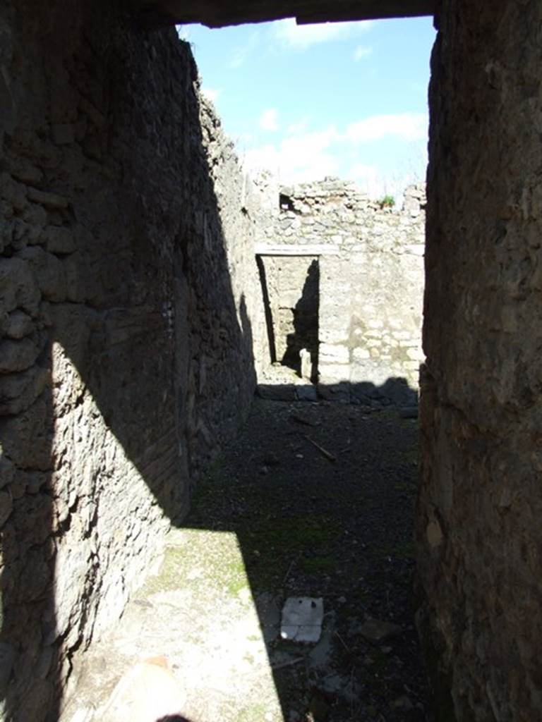IX.9.f Pompeii. March 2009. Looking east along entrance corridor to atrium. According to NdS, this was the doorway to a small and impoverished dwelling. The floor was made of somewhat tilted signinum, and the walls with rustic plaster and a high grey zoccolo. In both of the walls just near the door threshold, and at about 1.40m above the floor level, was a hole in which the beam was placed, to reinforce the closing of the door. Two other joints made for the usual diagonal beams were seen at the base of the walls, near the entrance into the atrium.
See Notizie degli Scavi, 1891, p.263