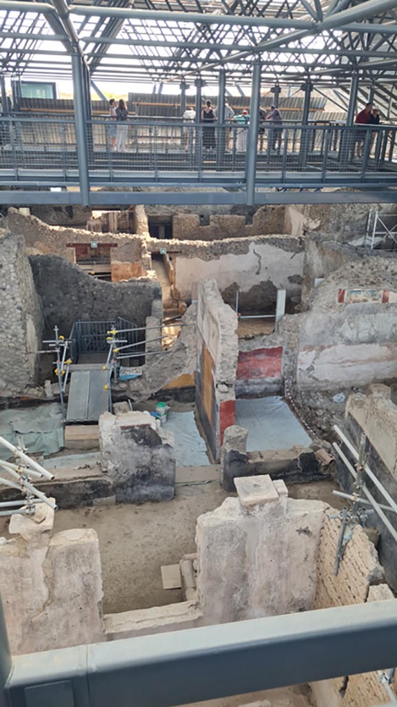 IX.12.4/6 Pompeii. June 2024.
Looking east from above IX.12.4. Photo courtesy of Giuseppe Ciaramella.
Looking east towards room “o”, with modern steps down into IX.12.6, and yellow and black painted walls.
Room “l(L)” with red walls is on its south side.
On the right is room “f”, with painting on upper wall, described as a painted zoccolo.