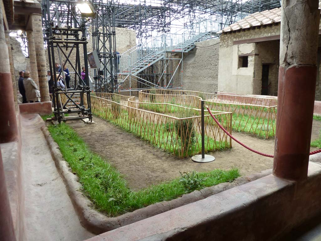 IX.12.9 Pompeii. May 2010.
Looking south-west across peristyle/garden area 5. Room 9 can be seen under the grey metal stairway.
According to an information card in the house -
“In the garden at the centre of the triporticus, the original design of the flowerbeds was reconstructed thanks to the imprints of the fences and casts of garden plants. The garden was also decorated with a fountain which was crowned with a statue of a young boy, on which we can identify traces of original colours.”