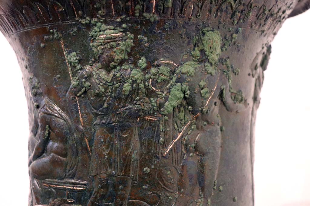 IX.13.1-3 Pompeii. February 2021.
Detail from bronze krater with scenes in relief, found in triclinium, on display in Antiquarium, VIII.1.4.
Two of the other standing armed male figures. Photo courtesy of Fabien Bièvre-Perrin (CC BY-NC-SA).