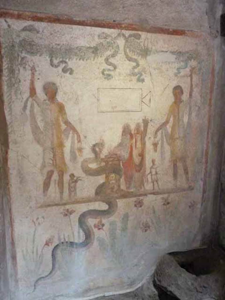 IX.13.1-3 Pompeii. May 2010. Room 21. Household Lararium.
Lararium by west wall of services atrium, near door to room 23, kitchen.
Two Lares, much taller than all the other figures, stand on either side.
A Genius and a small Tibicen and a round altar are between them.
By the round altar dressed in blue and red is Juno.
A large snake winds round the altar. See Fröhlich, T., 1991. Lararien und Fassadenbilder in den Vesuvstädten. Mainz: von Zabern. (L109).