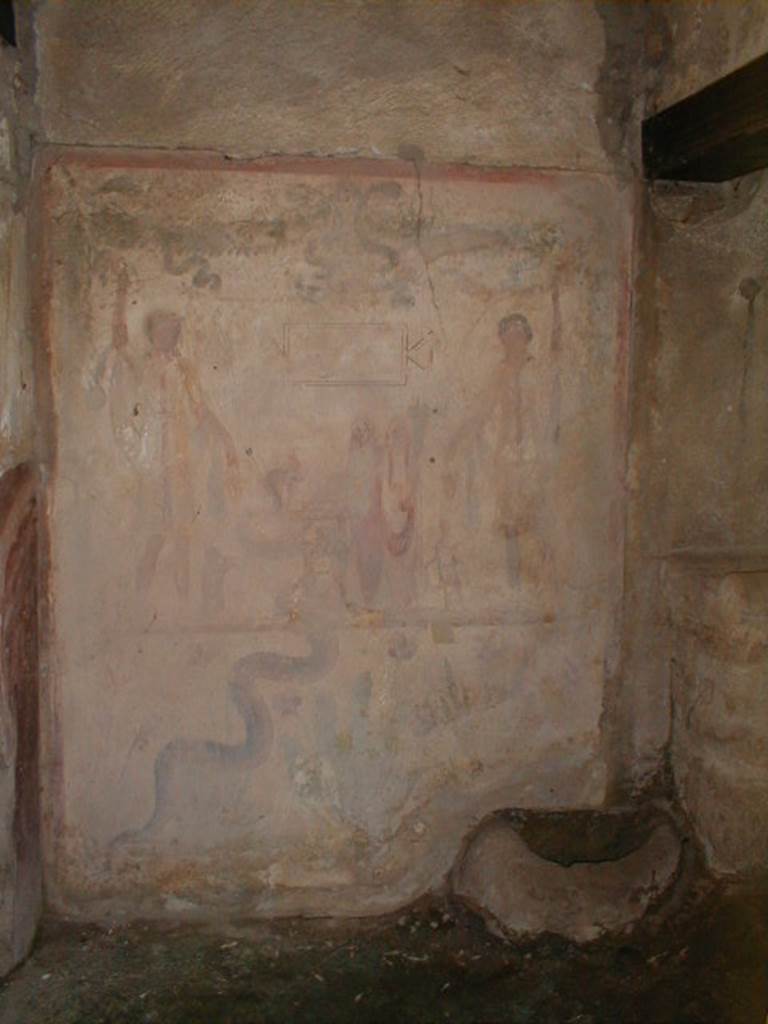 IX.13.1-3 Pompeii. September 2004. Room 21.
Lararium by west wall of services atrium, near door to kitchen.
Two Lares, much taller than all the other figures, stand on either side.
A Genius and a small Tibicen and a round altar are between them.
By the round altar dressed in blue and red is Juno.
A large snake winds round the altar. See Fröhlich, T., 1991. Lararien und Fassadenbilder in den Vesuvstädten. Mainz: von Zabern. (L109).