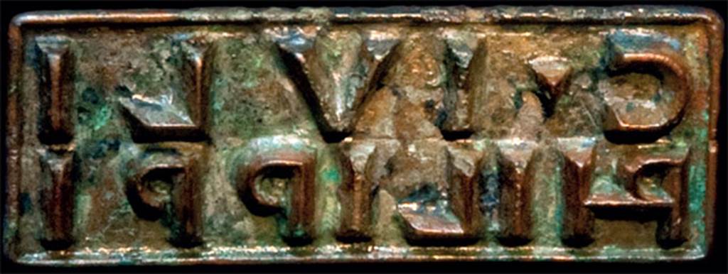 IX.13.1-3 Pompeii. 1973. Bronze seal of C. IULI PHILIPPI (Caius Iulius Philippus) found in chest in Room 9, east portico.
According to Varone, on the 8th February 1973 (7 January according to Giordano), along the eastern ambulatory of the house, wooden cabinets were discovered in one of which, between various precious objects, was found a bronze seal inscribed with C (ai) IVLI PHILIPPI. The bronze seal is a symbolically individual tool. It was used to mark, as a signature, for example, the veracity of the contents of a message. After engraving with the stylus, the wax tablets were folded one against the other to form a diptych, they were bound by a ribbon closed by sealing wax on which was stamped the seal of person who thus signed for the content. It will be understood, then, like the seal of a modern notary it constituted a personal element to be jealously guarded. It was in fact worn on his finger or kept in a safe. We cannot doubt, then, that Iulius Philippus lived in this house.
Graffiti in the house shows that Philippus and Polybius had a close relationship, which may have been father and son, but it is not clear who is which. However, I think, without wanting to go into a whole series of evaluations, but I think, though it would still be questionable, that it was most likely Philippus was the father of Polybius.
See Varone A., 2015. Indagine su un cittadino al di sopra di ogni sospetto: Giulio Polibio, in Caio Giulio Polibio, 2015. Napoli: IDSN, p. 97-8, p.104.