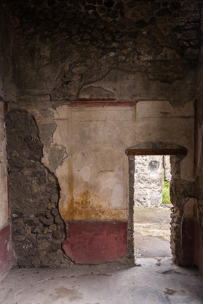 IX.14.4 Pompeii. July 2024. South wall of room F on the east side of the atrium.
The small doorway in the south wall led into the eastern ala G. Photo courtesy of Johannes Eber.