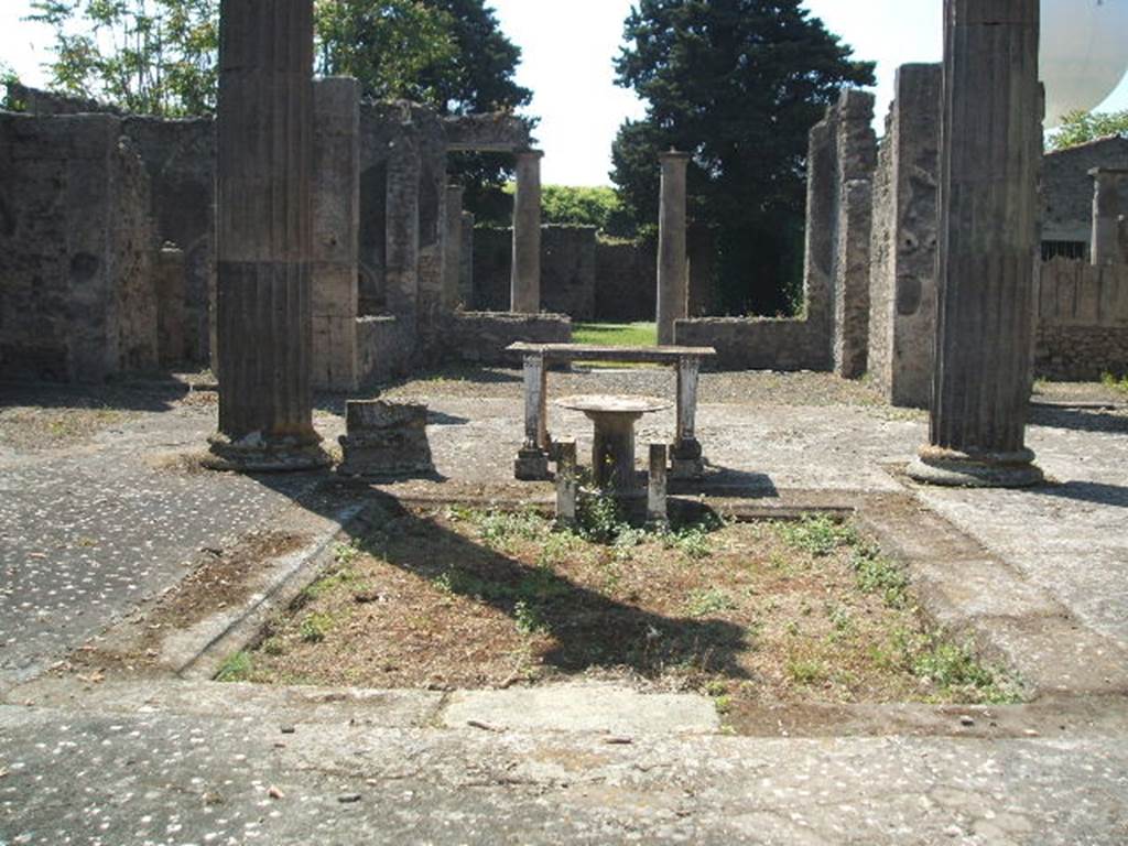 IX.14.4 Pompeii. May 2005. Looking south across impluvium in atrium B towards tablinum H. When discovered, the walls of the tablinum where covered with rough plaster, awaiting their coating of fine decoration. Found fixed on the south side of the atrium, on the side pilasters of the tablinum, were four figured bronze fittings, of two different types, (borchia figurata). 
The holes left by the removal of the four figured bronze fittings can be seen on each pillar of the tablinum entrance. See Notizie degli Scavi, 1905, (p.253-256).