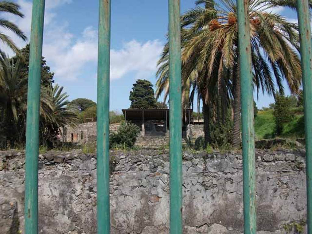 HGW24 Pompeii. May 2010. Looking east over garden towards the large room/loggia on the upper floor. This photo was taken from the road, and the masonry wall is the west wall of the portico area.