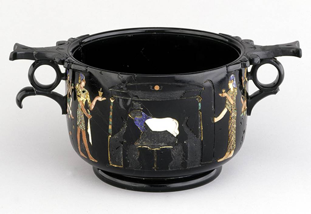 Castellammare di Stabia, Villa San Marco, Found May 1954, room 37, near the south east wall. Side of obsidian skyphos (cup) B with Egyptian scenes of ram worship inlaid in gold and mosaic. Now in Naples Archaeological Museum. Inventory number 294473.
