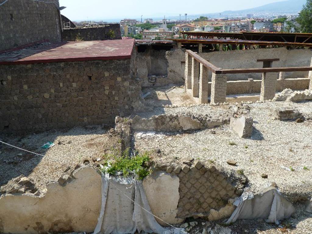 Villa San Marco, Stabiae, July 2010. Looking north. Photo courtesy of Michael Binns.
According to the descriptive information card –
“The latest archaeological researches have brought to light some of the northern (we describe as eastern) structures next to the atrium of Villa San Marco.
These structures have been partially known by the drawings made during the Bourbon excavations.
It is a sort of a trapezoidal peristyle directly linked to the tablinum of the villa.
The inner part of the peristyle was arranged as a garden with a large central tree.
On the north wing (we say east side) a monumental entrance, distinguished by two side semi-columns, is widely opened to the public way.
On the left it is possible to see a small room made by hurdle, probably used by the slave who served as doorkeeper.
On the west side (we describe as north side) two triangular rooms used as lavatories have been dug, in which several graffiti have been found.
Along the eastern front (we describe as the south side), there are a series of rooms, probably used as servants’ quarters or as food storage, while in the north-west wing (we describe as the north-east corner) a brick staircase was used to connect the ground floor with the first floor of the house.”
According to Keppie, this is a peristyle garden which would have been on the east of the atrium and tablinum.
Some elements originally exposed in the eighteenth century are being gradually opened up again.
See Keppie, L. (2009). The Romans on the Bay of Naples: an archaeological guide. The History Press, Stroud, Glos. (p. 148-9).
See Terpstra T, The 2011 Field season preliminary Report at http://www.fastionline.org/docs/FOLDER-it-2012-259.pdf