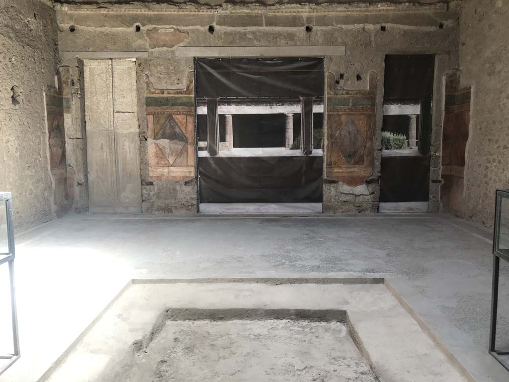 Villa of Mysteries, Pompeii. April 2019.
Room 64. Looking east across atrium towards blinds with photo of peristyle A imprinted on it, across two of the entrance doorways.
On either side of the impluvium is a display case containing a “body” plaster-cast.
Photo courtesy of Rick Bauer.