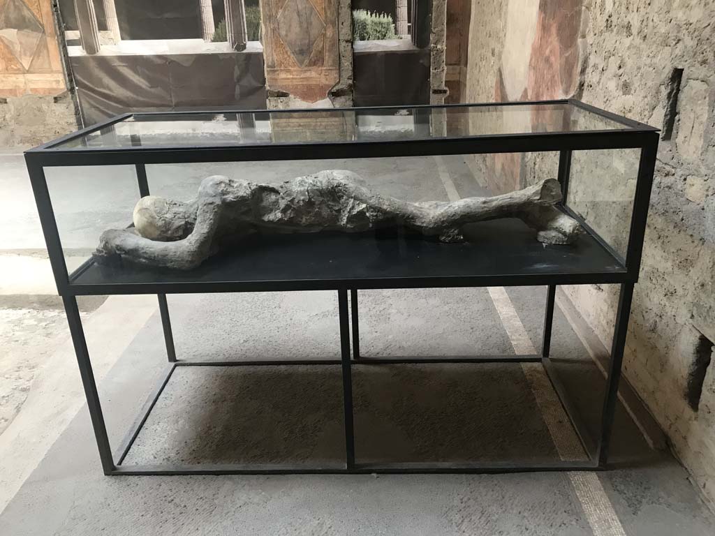 Villa of Mysteries, Pompeii. April 2019. Room 64, looking east across atrium towards display case on south-east side.
This contains the plaster-cast of a body of a man found in Room 35, on the other side of the peristyle.
Photo courtesy of Rick Bauer.