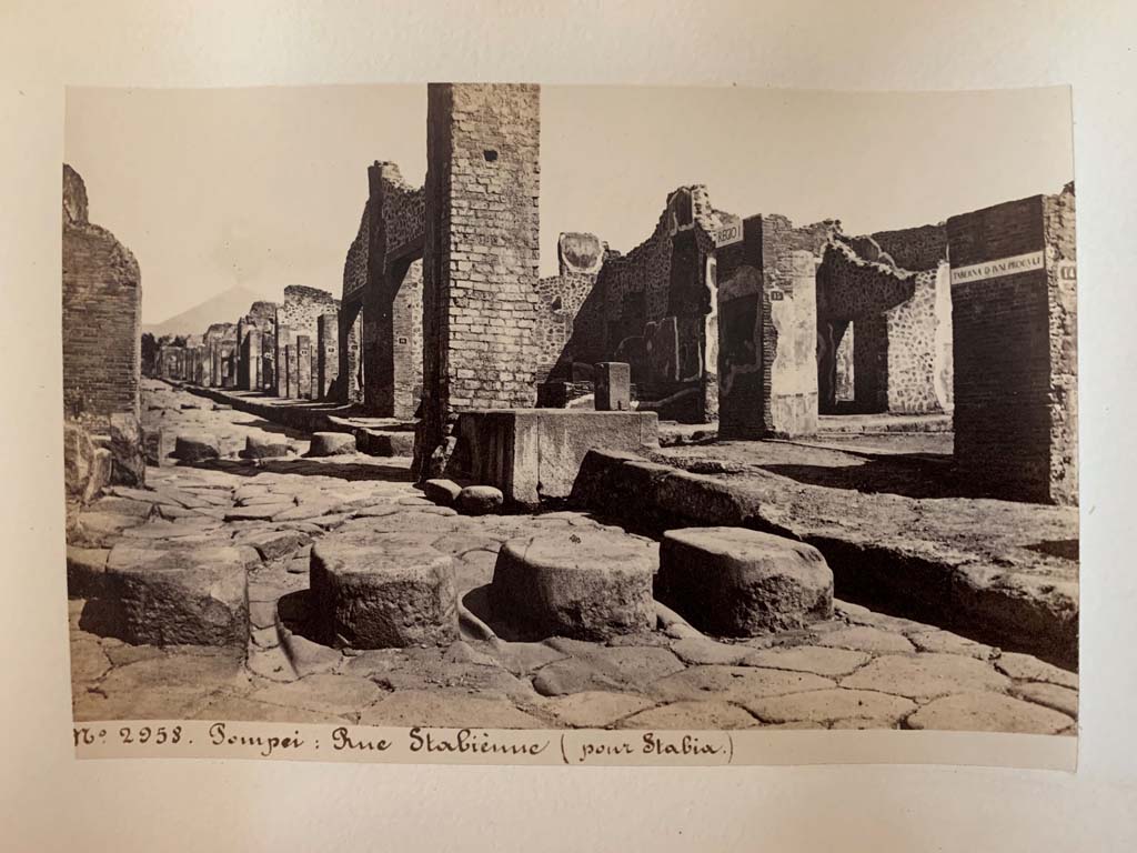 Via Stabiana, Pompeii. Album by M. Amodio, c.1880, entitled “Pompei, destroyed on 23 November 79, discovered in 1748”.
Looking towards fountain outside I.4.15, and continuation of roadway to north. On the right is the Via dell’Abbondanza.
Photo courtesy of Rick Bauer.