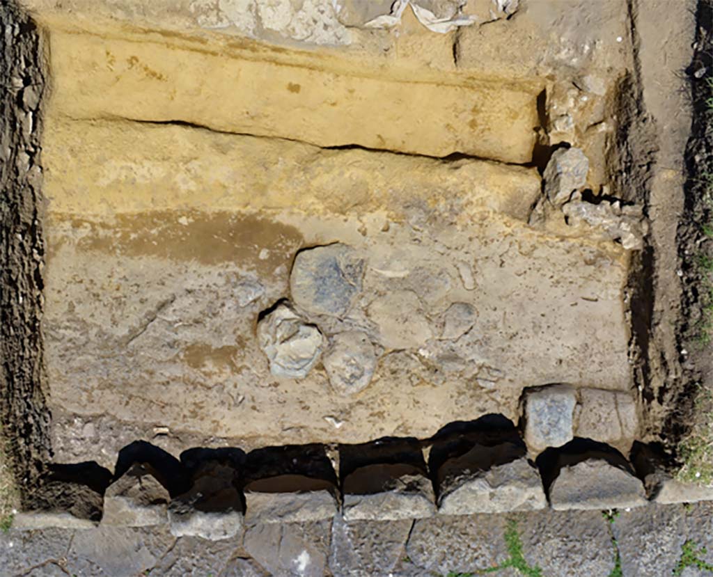 The oldest basalt road uncovered between the portico and the current paved road
Photo B. Lemaire, CJB CNRS/EFR - CC BY-NC-SA 4.0
We observed in two holes the remains of an older basalt road, lying at a lower level than the current one via dei Sepolcri, and having a slightly different orientation.
The negative trace left by the blocks of the sidewalk shows a fairly clear difference between the ancient route and the current road.
La route en basalte la plus ancienne mise au jour entre le portique et l’actuelle voie dallée.
Cliché B. Lemaire, CJB CNRS/EFR - CC BY-NC-SA 4.0
Nous avons pu observer dans deux sondages les restes d’une voie en basalte, plus ancienne, se trouvant à un niveau plus bas que l’actuelle via dei Sepolcri, et ayant une orientation légèrement différente.
La trace en négatif laissée par des blocs du trottoir permet d’observer une différence assez claire entre le tracé antique et l’actuelle voie.
Pompéi : Le secteur de la Porte d’Herculanum à Pompéi : Entre espace funéraire et commercial : organisation, gestion et transformations d’une zone suburbaine
https://centrejeanberard.cnrs.fr/spip.php?article107&lang=fr
