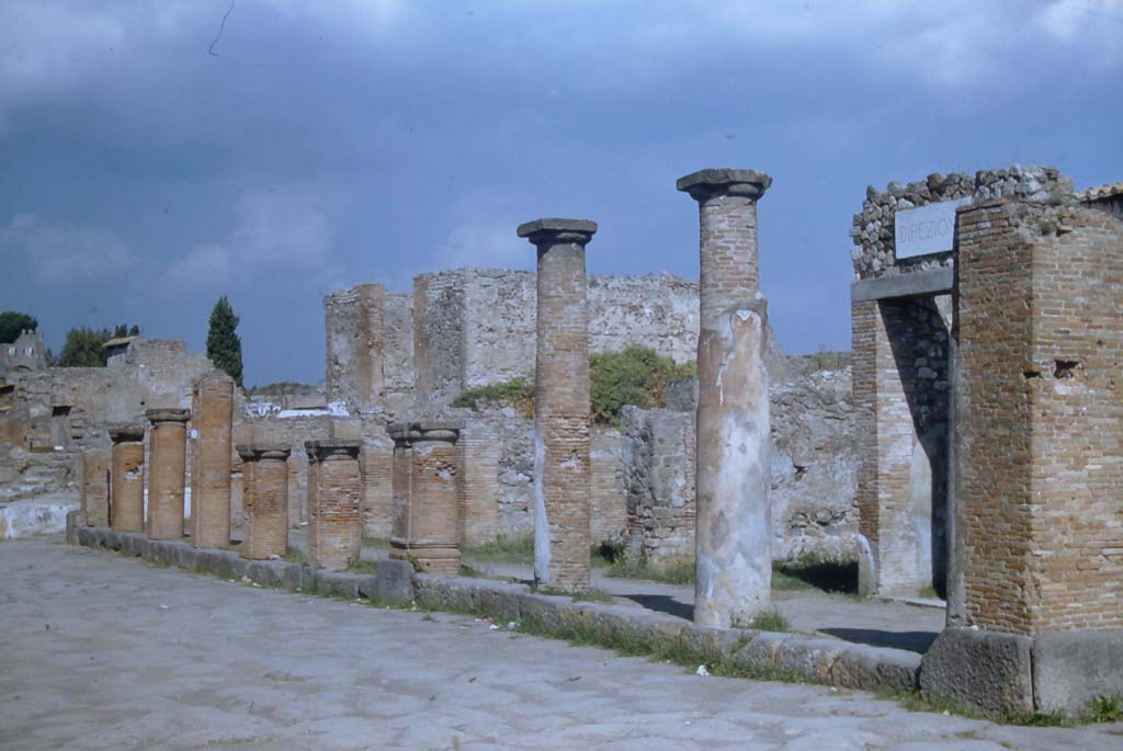 Via del Foro, Pompeii. November 1961.
Looking north towards east side of roadway with colonnade on VII.4, with Temple of Fortuna, in background.
Photo courtesy of Rick Bauer.