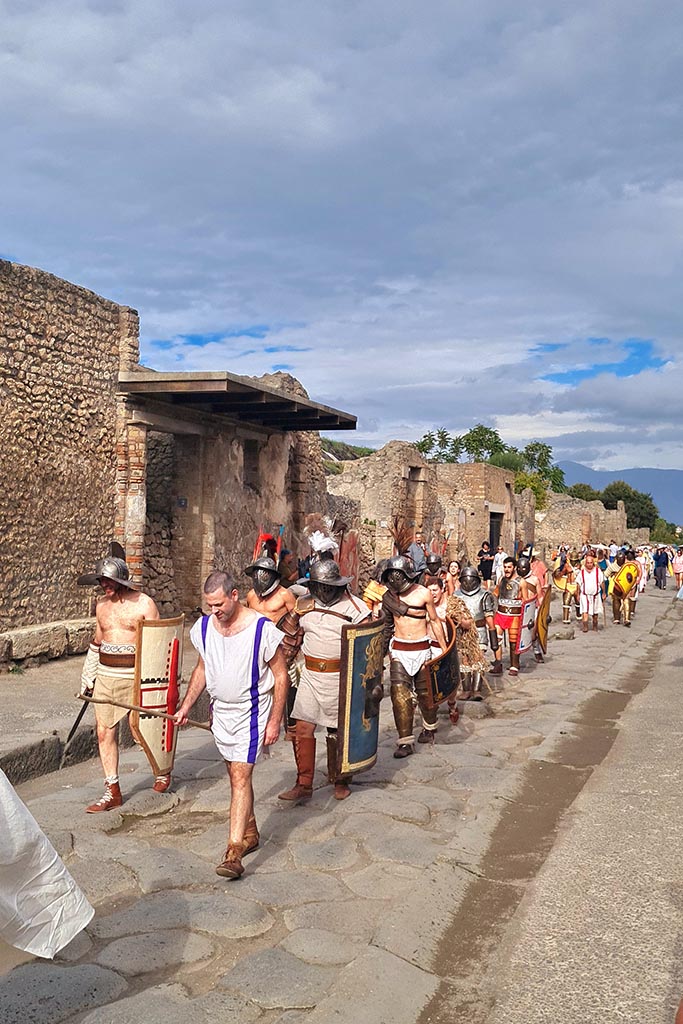 Via dell’Abbondanza, north side. 28th September 2024.
Gladiators on their way to the Forum from the Amphitheatre, during “Ludi Pompeiani” event.
Looking east along north side of Via dell’Abbondanza from III.5.2, on left. Photo courtesy of Giuseppe Ciaramella.
