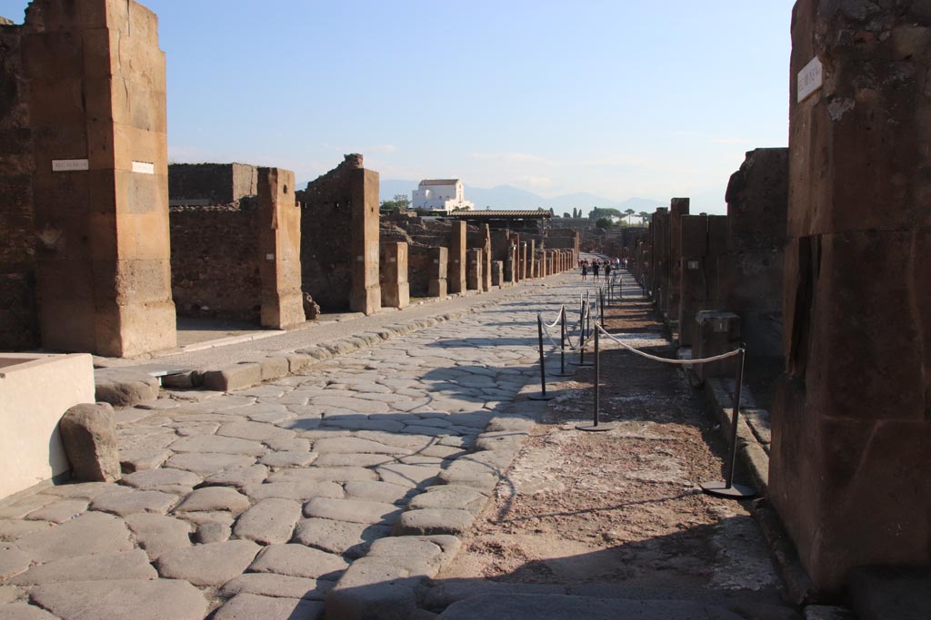 Via dell’Abbondanza, Pompeii. October 2022.
Looking east between VII.13, on left behind fountain, and VIII.5, on right. Photo courtesy of Klaus Heese.