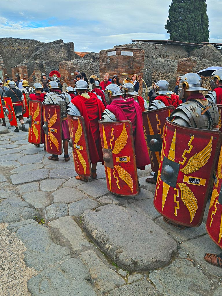 Via dell’Abbondanza, south side, Pompeii. 28th September 2024.
Legionaries with shields with the Cornicen at the side with the trumpet.
Looking south-east towards VIII.4.1 on east side of Via dei Teatri, during “Ludi Pompeiani” event.
Photo courtesy of Giuseppe Ciaramella.
