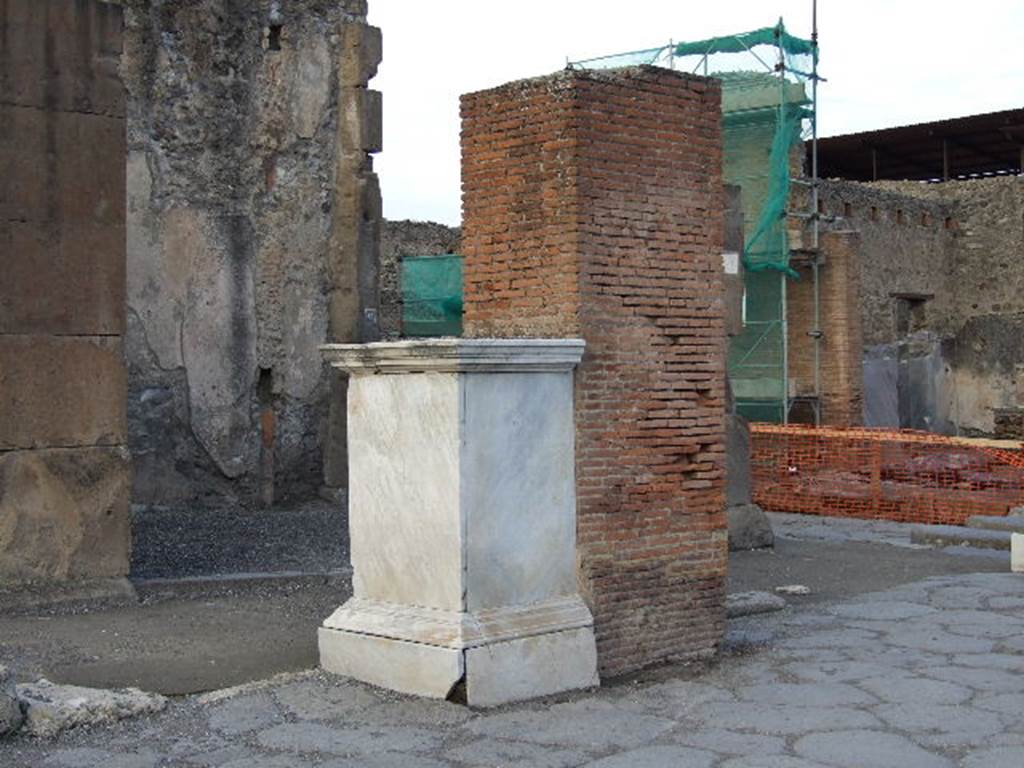 Via dell’Abbondanza, north side, with VII.1.12 in background behind pedestal which was the base of a statue of M. Holconius Rufus.
December 2006. The statue is now in Naples Archaeological Museum.
The brick pillar behind it was one of four which supported an arch over Via dell’ Abbondanza.