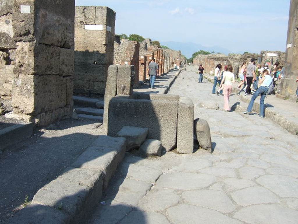 Via della Fortuna between VI.13 and VII.4. Looking east with Vicolo dei Vettii on left behind fountain. The crowd on the right is going into Vicolo Storto. May 2006.