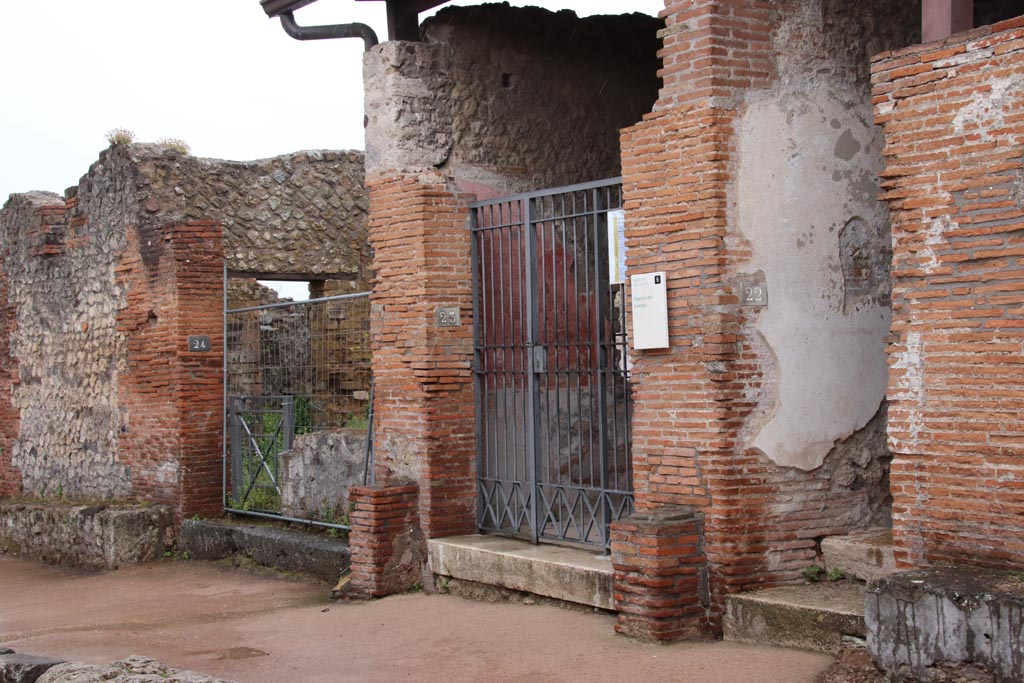 Vicolo della Regina, south side, Pompeii. May 2024. Entrance doorways to VIII.2.24, VIII.2.23 and VIII.2.22. Photo courtesy of Klaus Heese.