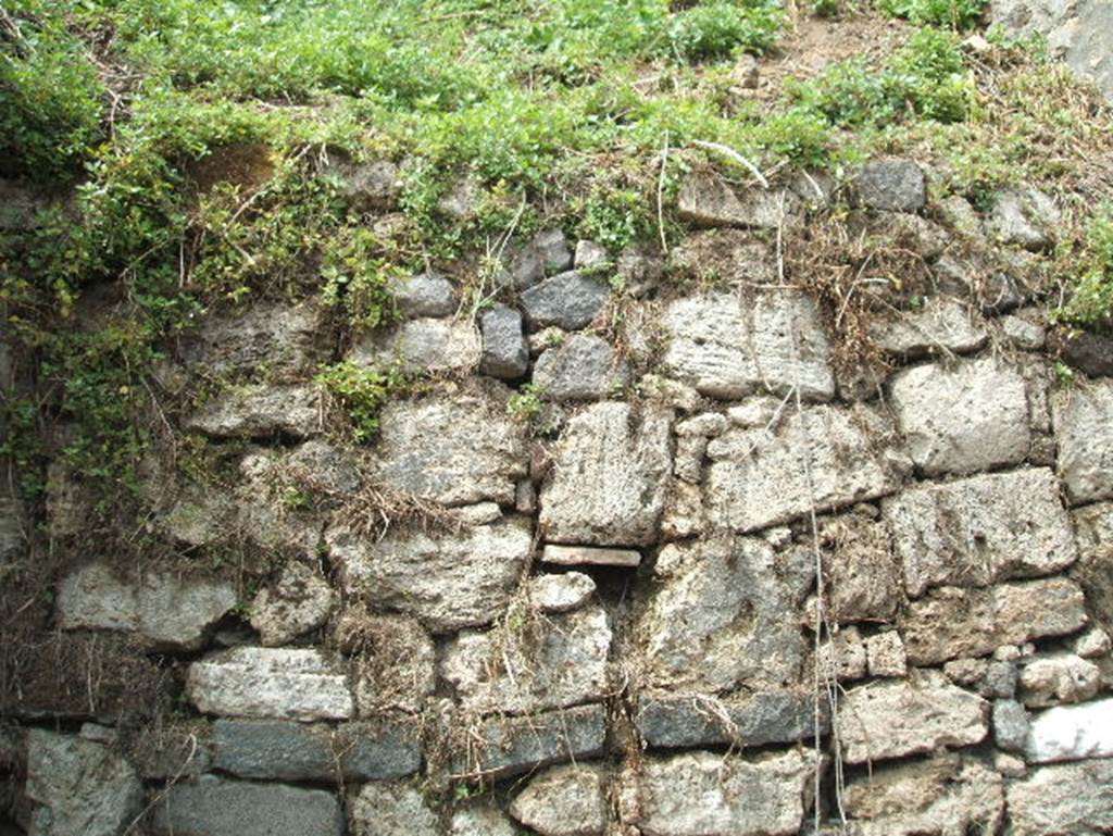 Vicolo delle Nozze d’Argento. May 2005. Looking north at blocked (partly unexcavated) road.
In 2018 excavation started here and the cleared road is being referred to as a continuation of Vicolo di Cecilio Giocondo.
The initial part of the continuation of Vicolo di Cecilio Giocondo was investigated between V.6 and V.7 to the North, after the intersection with the vicolo delle Nozze d’Argento.
Well visible, in section, is the height of the pumice layer that covered the city in the first phase of the eruption.
At the pavement level of the vicolo, which has no paving stones, is a beaten floor made up of mixed earth with various waste material (animal bones, ceramic fragments, a fishing hook, etc.).
On the east wall of the vicolo a white painted tabula ansata is partially visible, which was probably destined to host an inscription, perhaps a sign or an electoral inscription.