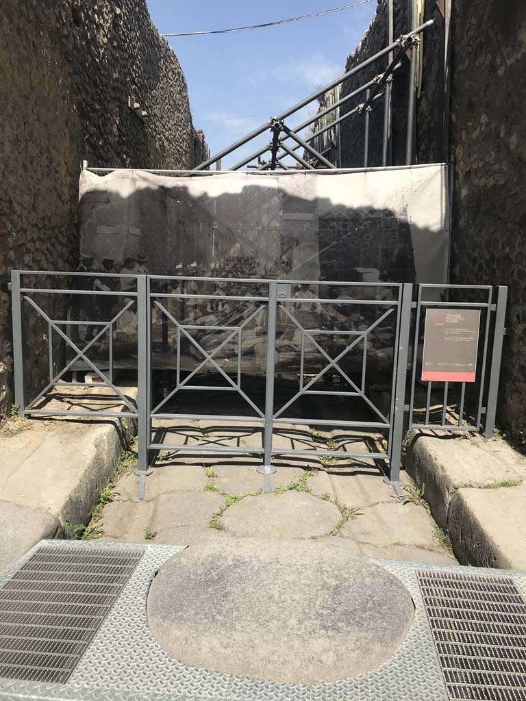 Vicolo di Tesmo between IX.1 and IX.7. April 2019. Looking north from Via dell’Abbondanza.
The screen hiding the vicolo shows an enlargement of a photo of the “first workers resting in the shade of the vicolo and posing for their photo.”
See Spinazzola, V. (1953). Pompei, alla luce degli Scavi Nuovi di Via dell’Abbondanza, 1910-1923. (p.31, fig.30)
Note the modernised accessible stepping-stone in the above photo. Photo courtesy of Rick Bauer.