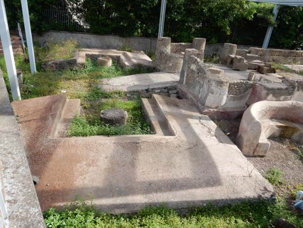 Tempio dionisiaco in località Sant’Abbondio di Pompei. May 2018. Looking north across the triclinium B and ramp C.
Photo courtesy of Buzz Ferebee.
According to Soprano –
Santuario dionisiaco sito in localita S. Abbondio (agro di Pompei), scavato nel 1947-48.
Dimensioni: L. medius, m.7.60; l. imus e summus, m.5.00; diametro delle mense, m.0.83.
Davanti al tempio si estendono due grandi triclini in muratura di eguali dimensioni e di ampiezza quale non si riscontra a Pompei.
Entrambi sono rivestiti di intonaco rosso e hanno la mensa circolare.
Lungo le pareti interne di ciascuno di essi corre un gradino sporgente (cm.26).
See Soprano, P. (1950). I triclini all’aperto di Pompei. (In Pompeiana, raccolta di studi per il secondo centenario degli scavi di Pompei. Napoli, Gaetano Macchiaroli, Editore, p.304, no.22.