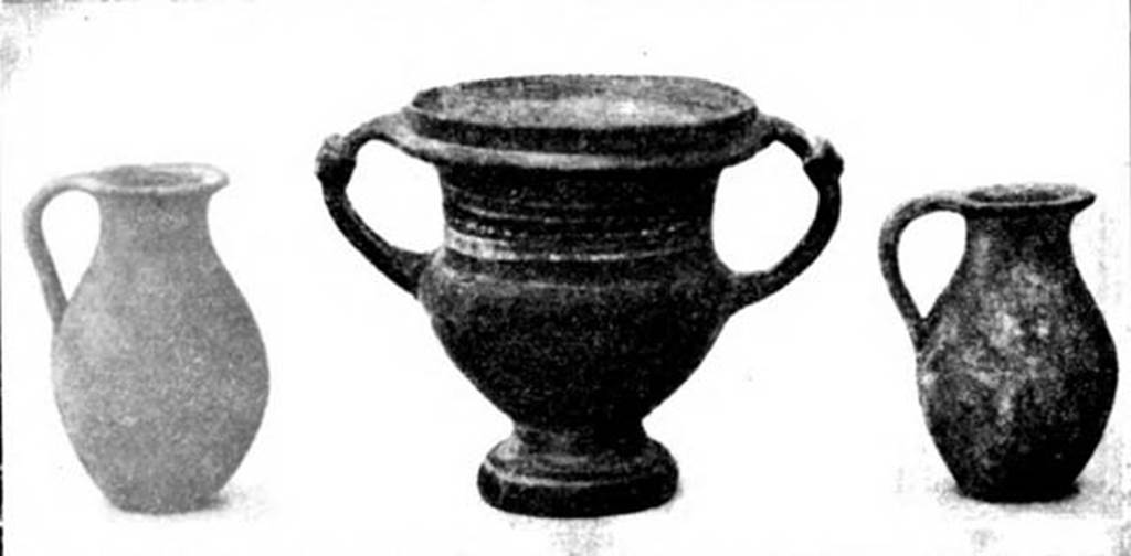 Pompeii Fondo Azzolini. Samnite Tomb III.
Three of the four vases found to the left of the skull.
Left is a small single handled jug, found inside the olla.
Right is another similar single handled jug.
Centre is a krater covered in shiny black varnish, decorated with a row of white dots between two bands, all running round between the two handles.
See Notizie degli Scavi di Antichità, 1911, p. 110, fig. 5).