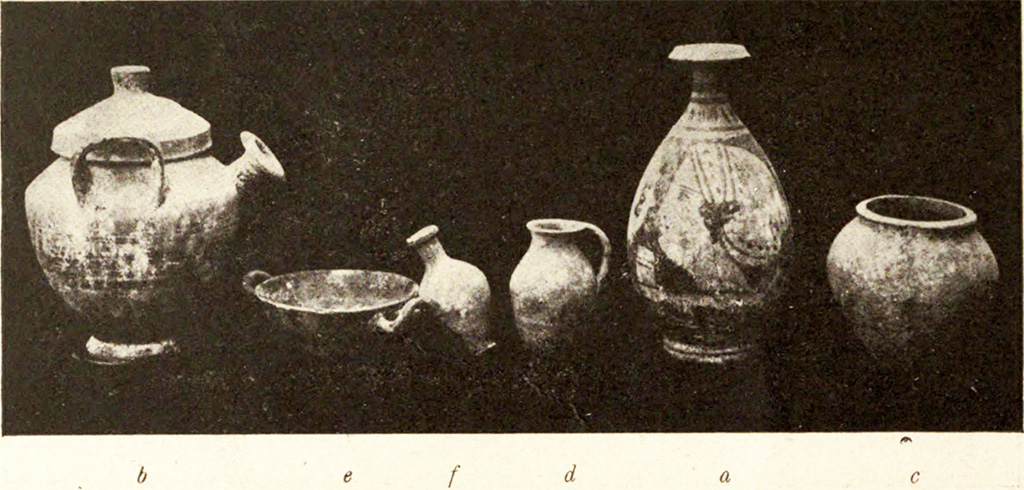 Pompeii Fondo Azzolini. Tomb VI. The photo above shows numerous objects found in the tomb.
b) Pot-bellied pitcher with vertical handles with lid (2): height 0.20 m., and on the shoulder are the dark slats that are repeated on the lid; between the handles, from the shoulder, protrudes a cylindrical bell-shaped spout.
e) Black-painted kylix, 0.11m in diameter, in whose bottom are the remains of a floral meander before graffiti and then painted with small white leaves.
f) Rustic ovoid jar with short neck, height 0.09 m.
d) Rustic flask, height 0.085m., with a shapeless surplus of iron in the base.
a) Lekythos, oval vessel, high 0.20 m, short neck: On a yellow clay background a female head in profile to the left is painted in black, while the opposite side is a palm between two whorls.
g) Iron blade, length 0.13m., broken in two pieces.
h) Arc shaped bronze buckle, from a strap. Width 0.027m.
c) Small rustic jar in the form of a dolium, height 0.11m.
See Notizie degli Scavi di Antichità, 1916, p. 292-3, fig. 3.
