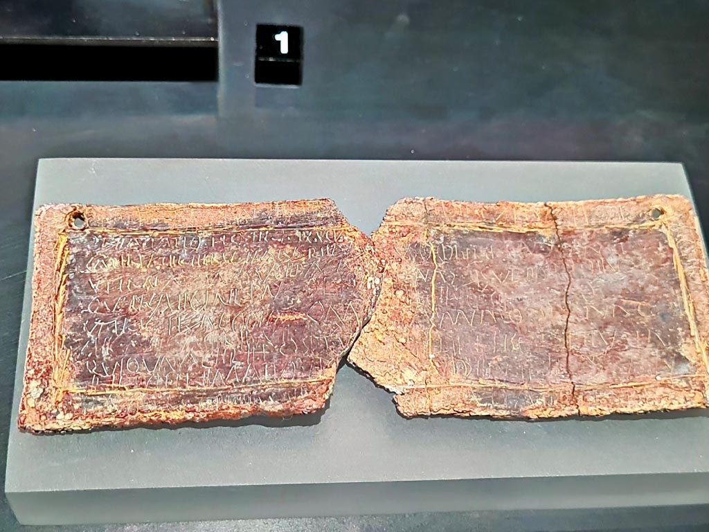 Pompeii Fondo Azzolini. Tomb 10. March 2024. Lead curse tablets.
According to the exhibition information card this is a tablet with curses from a woman to a freedwoman? Female slave?
Photo courtesy of Giuseppe Ciaramella.
On display in exhibition in Palaestra entitled - “L’altra Pompei, vite comuni all’ombra del Vesuvio”